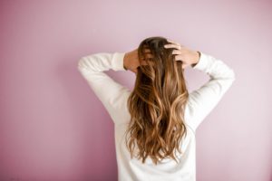 Femme de dos qui passe les mains dans ses cheveux