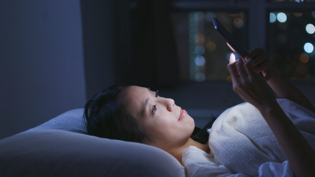 Femme utilisant son téléphone au lit